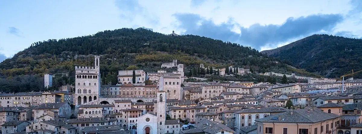 Gubbio mit dem Palazzo dei Consoli vor bewaldeten Bergen